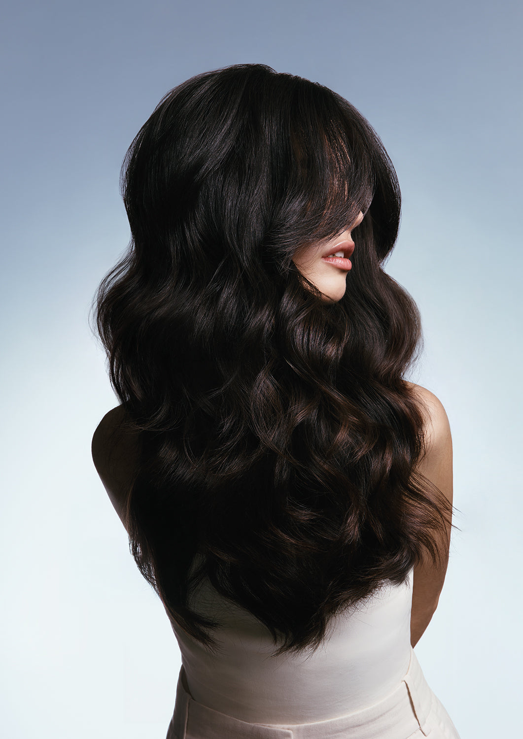 Model photographed from behind with a voluminous soft-waved brunette blowout